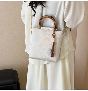 Detail view of floral printed handbag featuring a bamboo handle and tassel accent