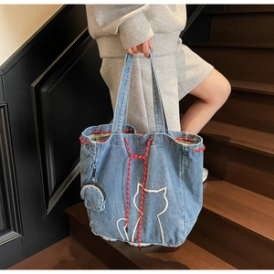 Detail of light blue denim tote bag with cat embroidery and red woven drawstring