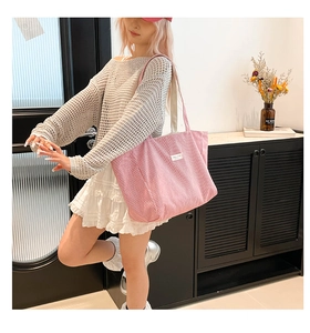 Gros plan du sac cabas en velours côtelé rose avec texture rayée et étiquette blanche