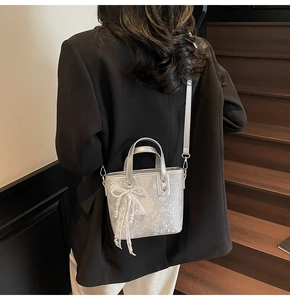 Schicke silberne Eimertasche mit Schlangenhaut-Prägung, Perlen-Spitzenschleife und Gurt