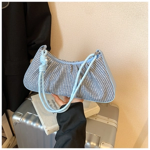 Macro shot of light blue woven pleated handbag with wave texture and knotted rope strap