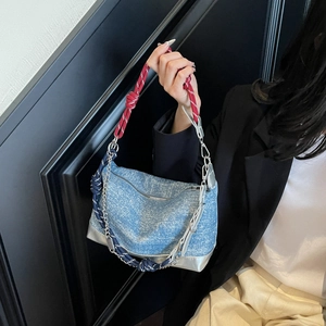 Detail of light blue denim tote with unique braided rope handles and silver chain accents
