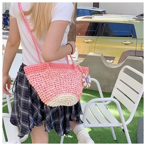 Detailed knit texture of pink and beige straw tote bag with purple flower charm