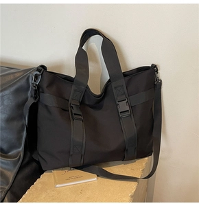 Macro shot of durable black canvas tote showing buckle closure and tactical webbing straps