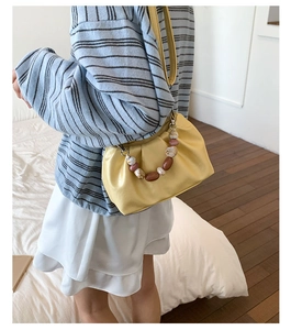 Detail of yellow pleated cloud bag with marble bead handle and thin leather strap