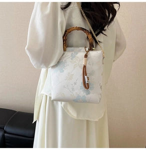 Detailed view of floral jacquard fabric with bamboo handle and metal chain on a crossbody bag