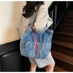 Detail of blue denim tote bag with cat embroidery and red-white drawstring cord