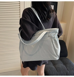 Grand sac cabas en nylon bleu clair porté par un mannequin dans une pièce minimaliste