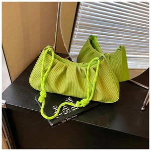 Close-up of neon green ruched bag with woven texture and knotted rope shoulder strap