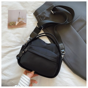 Detail of black nylon crossbody bag with adjustable wide strap and silver metal zippers
