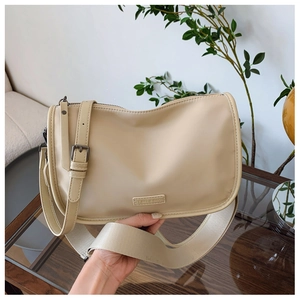 Détail du sac demi-lune beige avec bandoulière en cuir et large sangle en tissu tressé