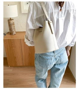 Detail of soft lychee pattern leather bucket bag with adjustable shoulder strap and metal buckle