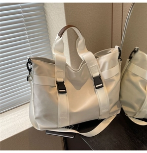 Detail of white nylon tote bag with leather handles and adjustable shoulder strap
