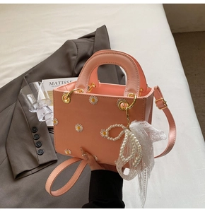 Close-up of pink tote bag featuring daisy embroidery, pearl beads and white lace trim detail