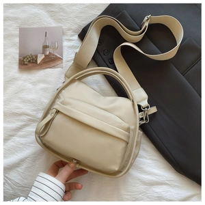 Detail of a creamy nylon crescent bag with adjustable wide strap and front zip pocket