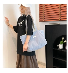 Grand sac cabas en toile à rayures bleues et blanches porté par un mannequin chic