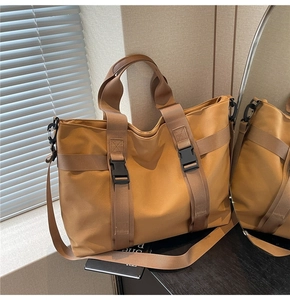 Detail of camel canvas tote bag with adjustable shoulder strap and black buckles
