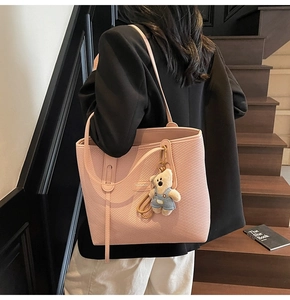 Rosa Tragetasche in Weboptik mit süßem Teddybär-Anhänger auf einer Holztreppe im Haus