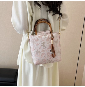 Detail of floral butterfly lace handbag featuring bamboo handle and gold chain strap
