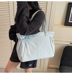 Gros plan d'un sac cabas en nylon bleu clair avec côtés plissés et rivets en métal