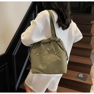 Detail shot of army green nylon bucket bag with drawstring closure and silver rivets