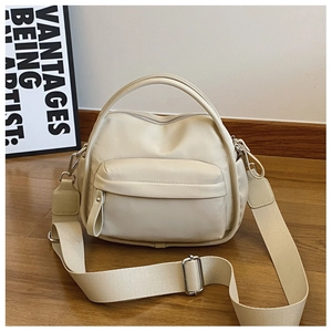 Detail of beige nylon crossbody bag with wide woven strap and silver metal buckle