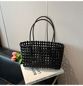 Detail of black hollow-out woven tote bag with slim handles for beach vacations