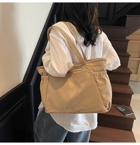 Détail d'un grand sac fourre-tout kaki avec plis latéraux et boucle en métal sur la bandoulière
