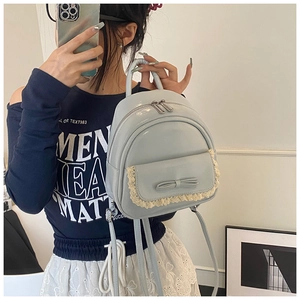 Detail eines gletscherblauen glänzenden Mini-Rucksacks mit Spitze und Schleife