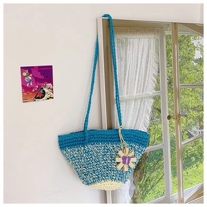 Macro detail of tricolor hand-knitted crochet tote bag with sunflower pendant charm