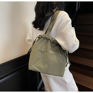 Macro shot of sage green nylon bucket bag featuring large cargo pockets and drawstring detail