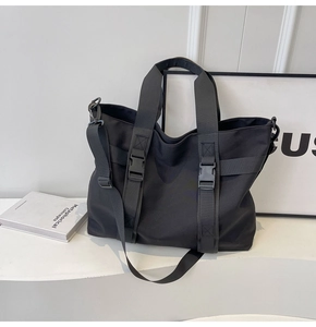 Detailed view of black canvas tote bag with adjustable buckles and detachable shoulder strap