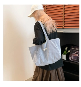 Détail du sac cabas en toile à rayures bleues avec une étiquette tissée minimaliste blanche