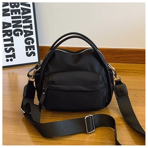 Close-up of black nylon crossbody bag with silver zippers and wide adjustable strap