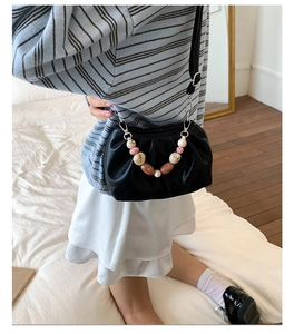 Detail of black pleated bucket bag with decorative marble effect beaded handle and strap