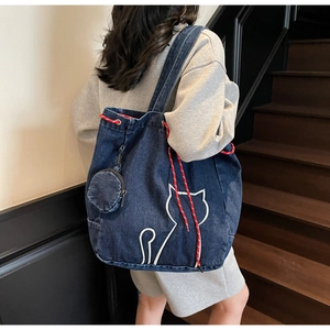 Close-up of large blue denim tote bag featuring white cat embroidery and a round coin purse