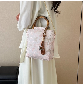 Detail of floral butterfly handbag featuring retro bamboo handle and chain strap