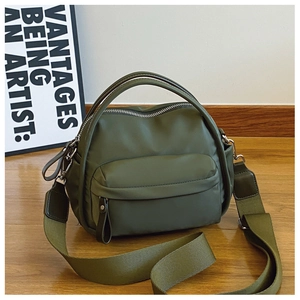 Detail of olive green nylon crossbody bag with dual handles and wide fabric strap