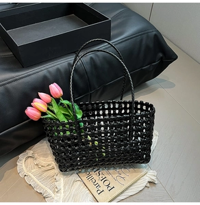 Detail of hand-woven black hollow mesh structure and slim round handles on a beach tote