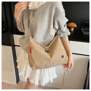 Detail view of khaki nylon crossbody bag featuring stylish logo patches and wide shoulder strap