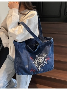 Blue denim tote bag featuring white spider web embroidery and red spider details