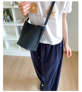 Close-up of black lychee-textured bucket bag showing soft leather and adjustable strap