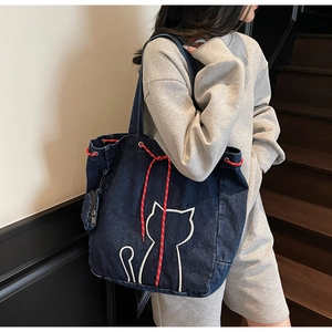 Detail of navy denim tote bag with cat embroidery and red drawstring with mini pouch
