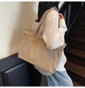 Détail du grand sac cabas kaki avec fronces latérales porté à l'épaule par un mannequin
