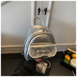 Detailansicht des silbernen Metallic-Rucksacks mit 3D-Schleife und Spitzenbesatz