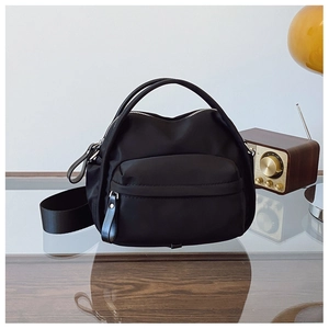 Close-up of black nylon crossbody bag with dual handles and detachable wide shoulder strap