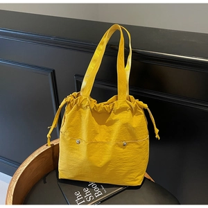 Detail view of yellow nylon tote bag with drawstring closure and front snap pockets