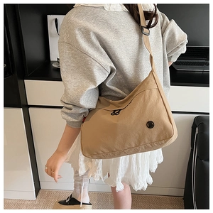 Side view of a khaki large-capacity nylon crossbody bag worn with a casual outfit