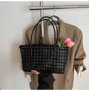 Close-up of black woven beach tote bag with thin straps and decorative pink tulip