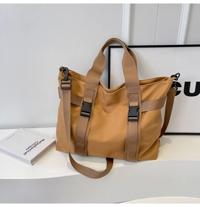 Detail view of khaki canvas tote bag with black buckles and adjustable shoulder straps